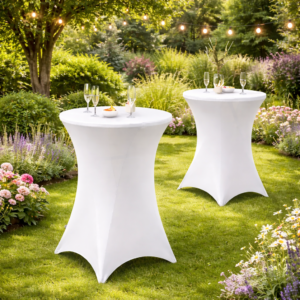Deux tables mange-debout avec housses stretch noires dressées dans un jardin fleuri pour cocktail en plein air